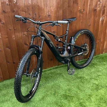 Black bicycle on green grass with a wooden fence background